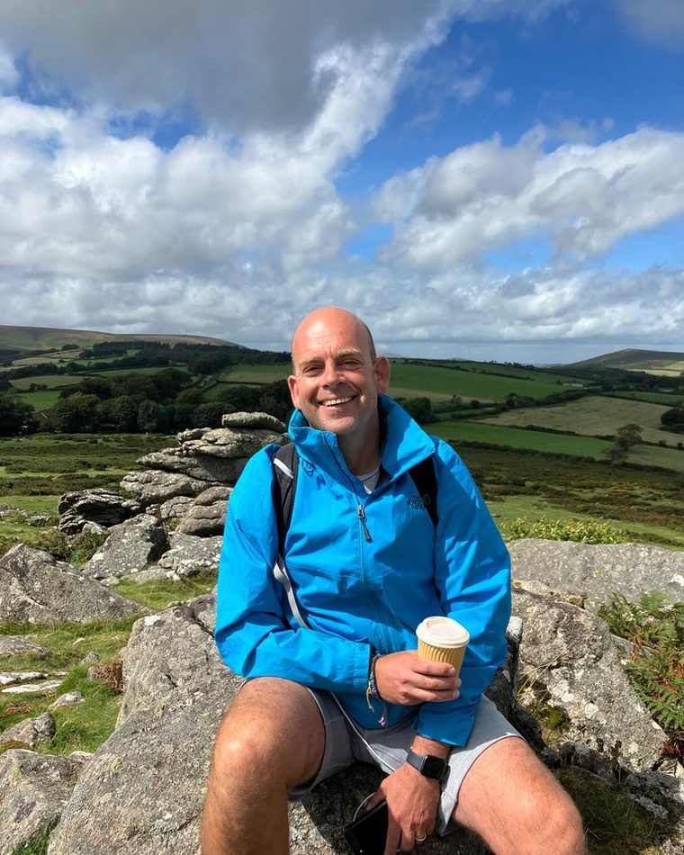 Steve Heath sitting on a tor on Dartmoor with a cup of coffee